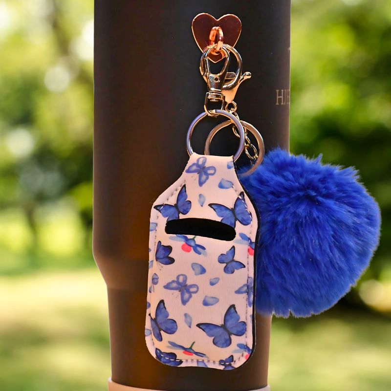 Blå veske til airpods som man foreksempel kan henges på termokoppen med krok. Den kan også henges andre plasser som på sekken, nøkkelringen eller jakken. Da har du alltid kontroll på hvor airpodsene dine er til en hver tid. Disse er håndlaget og denne har sommerfugler på seg med hvit bakgrunn og blomster.