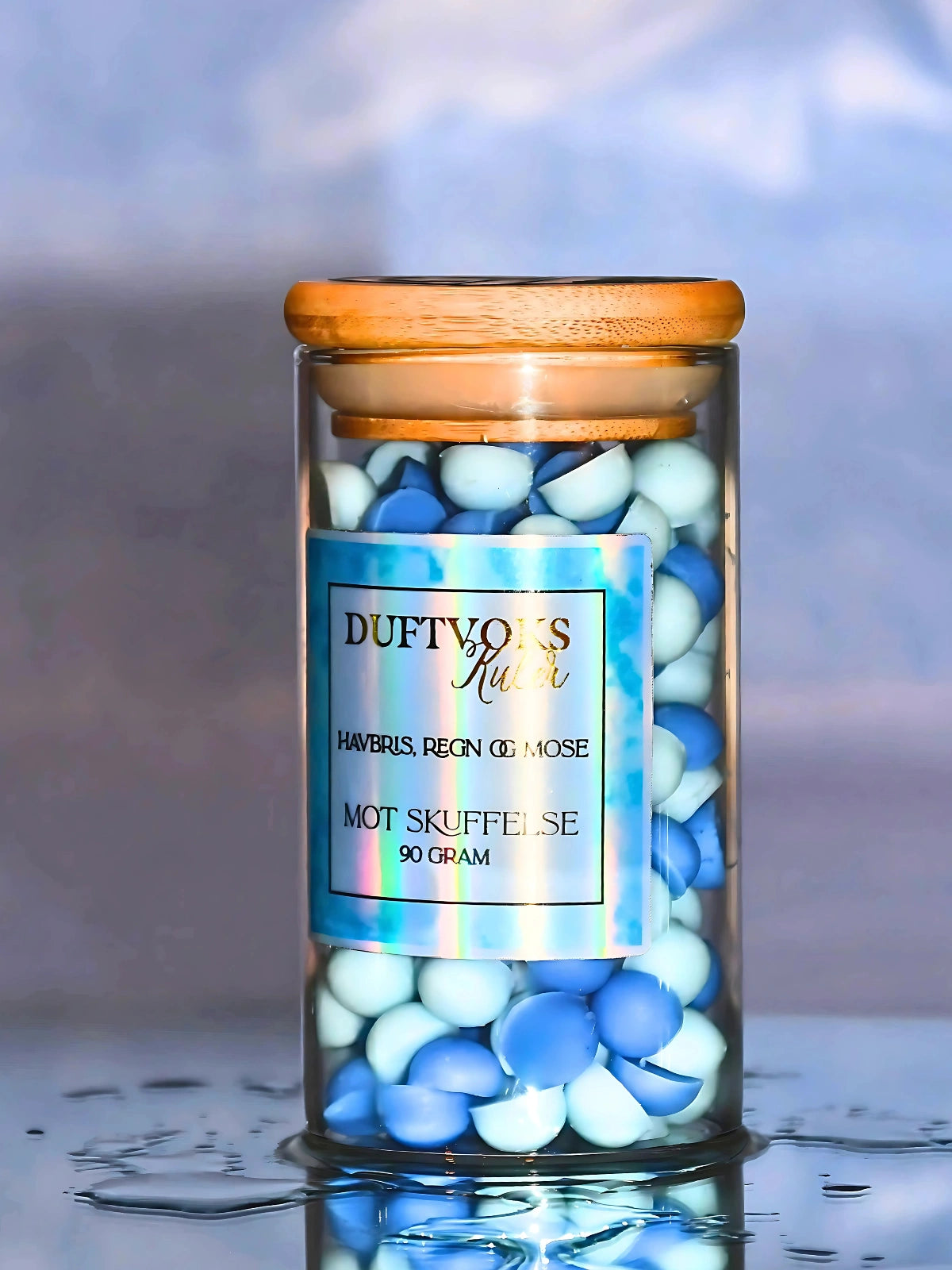 Duftvoks kuler i glass krukke som står i vann siden den dufter regn, havbris og mose. Lyse og mørke blå søte kuler som er håndlaget.
