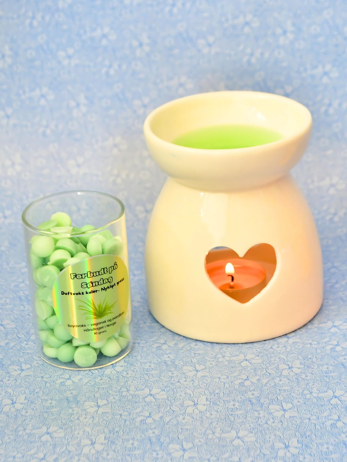 Duftvoks i bruk i duftbrenner. Små grønne kuler med lukten av gress. Vegansk og parafinfri soyavoks i flott glassbeholder.