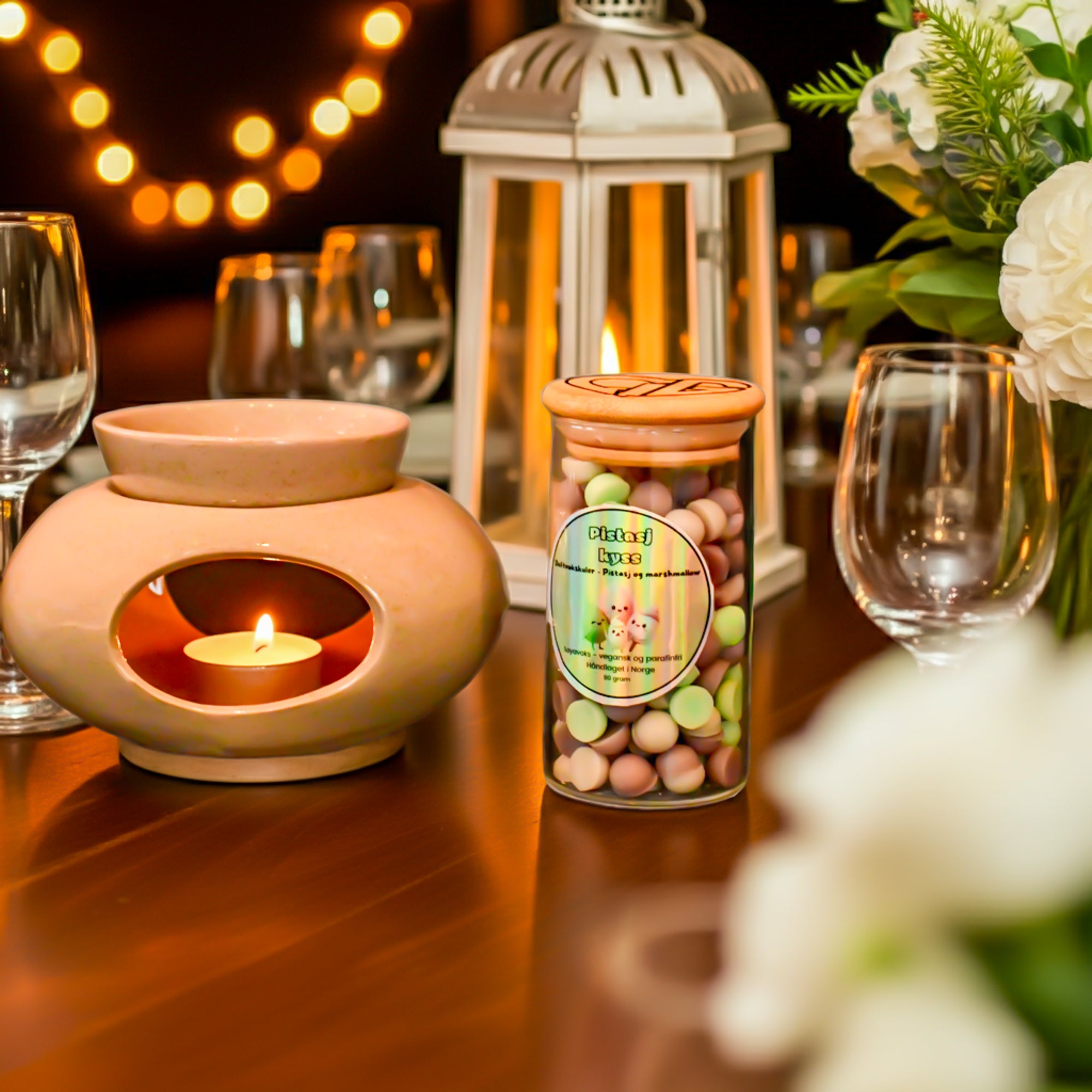 Håndlagde duftvokskuler i glasskrukke i bruk. Her står duft voks krukken vesiden av duftbenneren med telys inni. Telyset vil smelte duft voks kulene som ligger på toppen av brenneren og dermed vil rommet fylles med duften av marshmallow og pistasj. Dette er en unik og herlig lukt man bare må teste! Fantastisk julegave til noen som er glad i deilig og unike dufter.