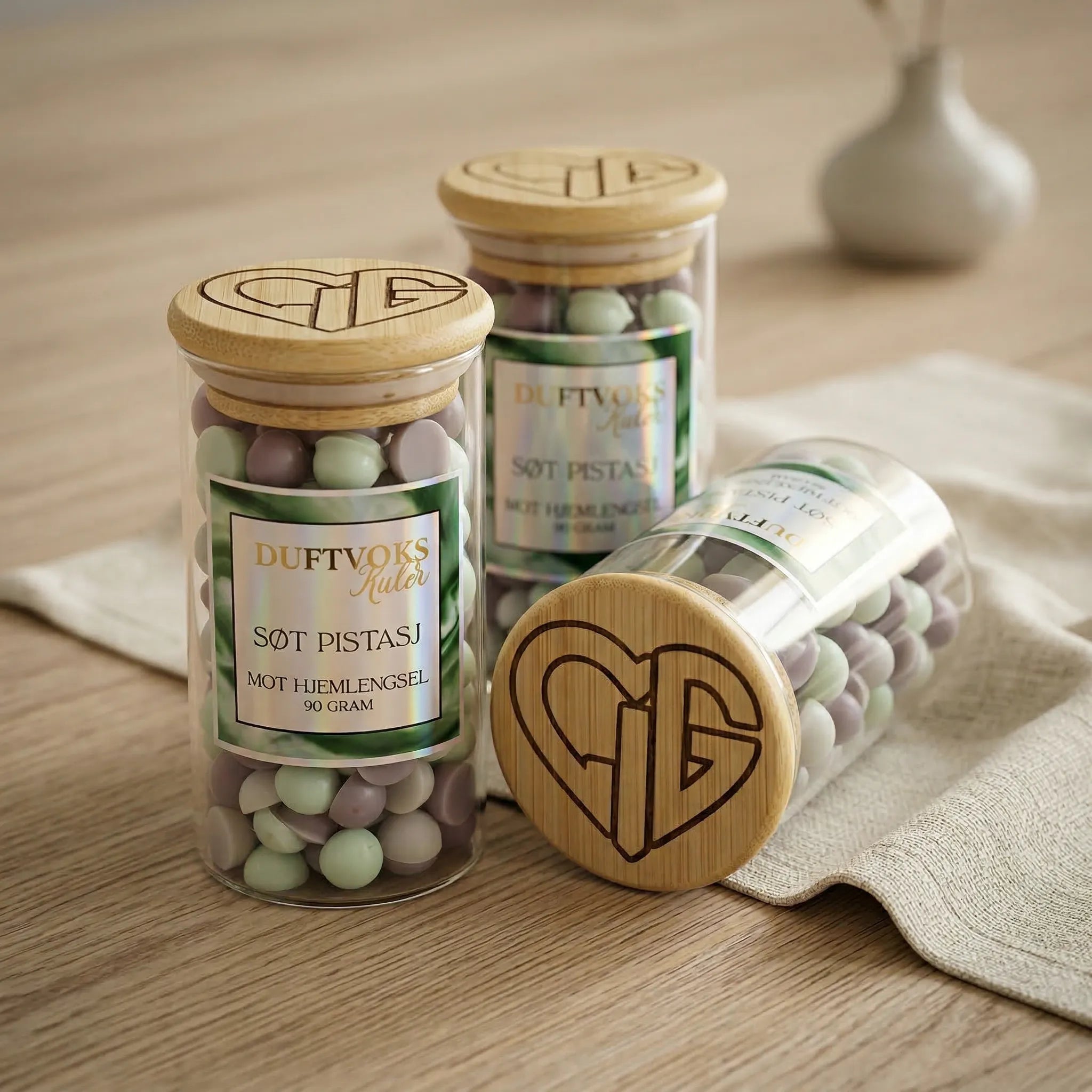 Glass med duftvoks med duft av søt pistasj. En duft som skal lindre følelsen av hjemlengsel. Håndlaget duftvoks med bivoks og soyavoks. Duftvoksen har beige og lys grønn farge. Hvert glass inneholder 90 gram duftvoks. En av flere dufter i serien "sett en duft på dine følelser"