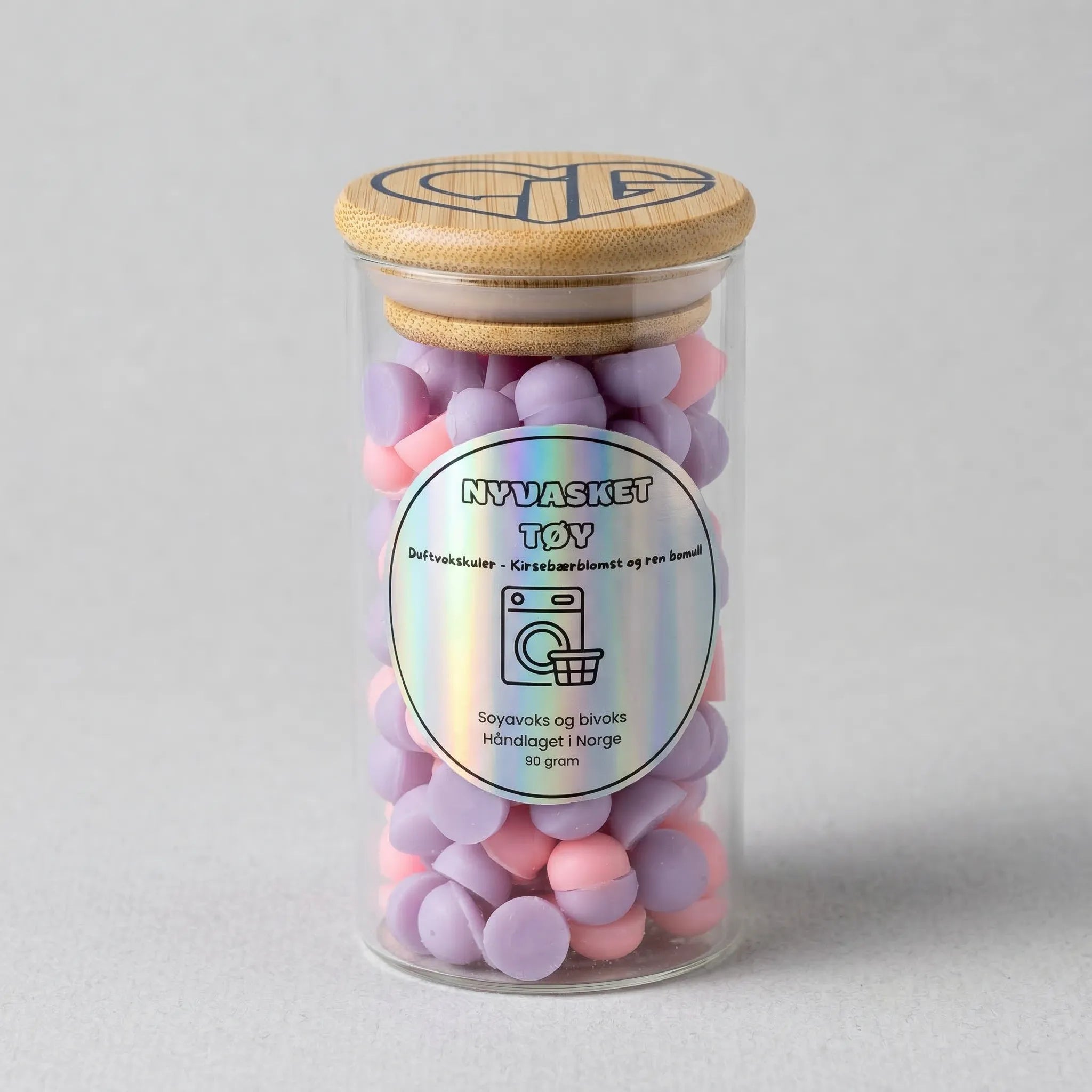 Håndlaget duftvoks som lukter nyvasket tøy. Laget med soyavoks og bivoks. Små kuler av voks i lilla og lys rosa farge. Brukes sammen med en duftbrenner som smelter vokskulene, slik at rommet fylles med nydelig duft. Glasset inneholder 90g voks.