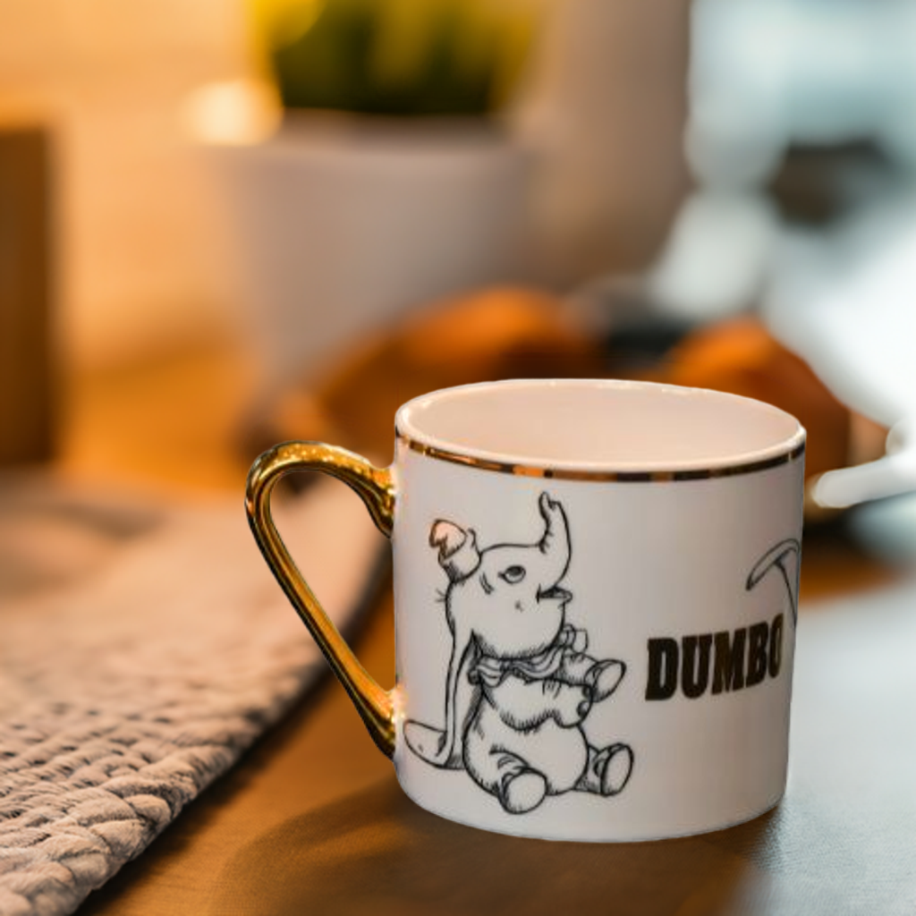 Dumbo koppen med gulldetaljer. Her ser man ene siden av koppen hvor det er bilde av Dumbo som baby og med teksten Dumbo.