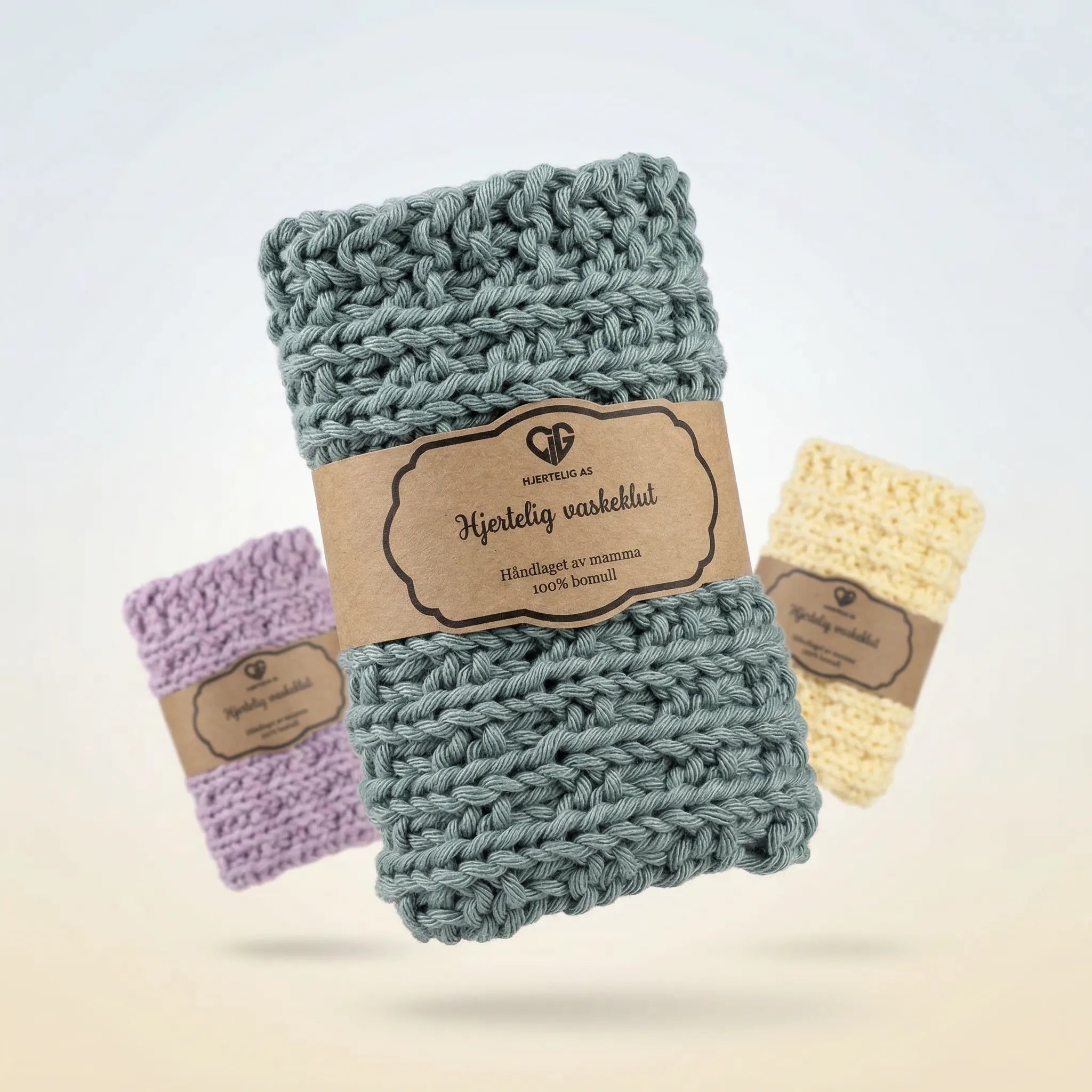 Grønn. vaskeklut i front, med håndlaget magehelte i resirkulert papir. Vaskekluten er håndstrikket av mamma og kommer i 6 forskjellige farger. De selges i pakker på 1stk, så velg din favorittfarge.
