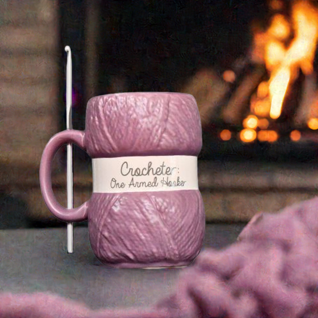 Lilla hekle kopp forran peisen med heklenålen i håndtaket. Heklesaker framst.