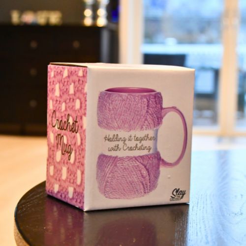 Hekle-krus i esken sin. Med bilde av hekling og koppen utenpå esken.