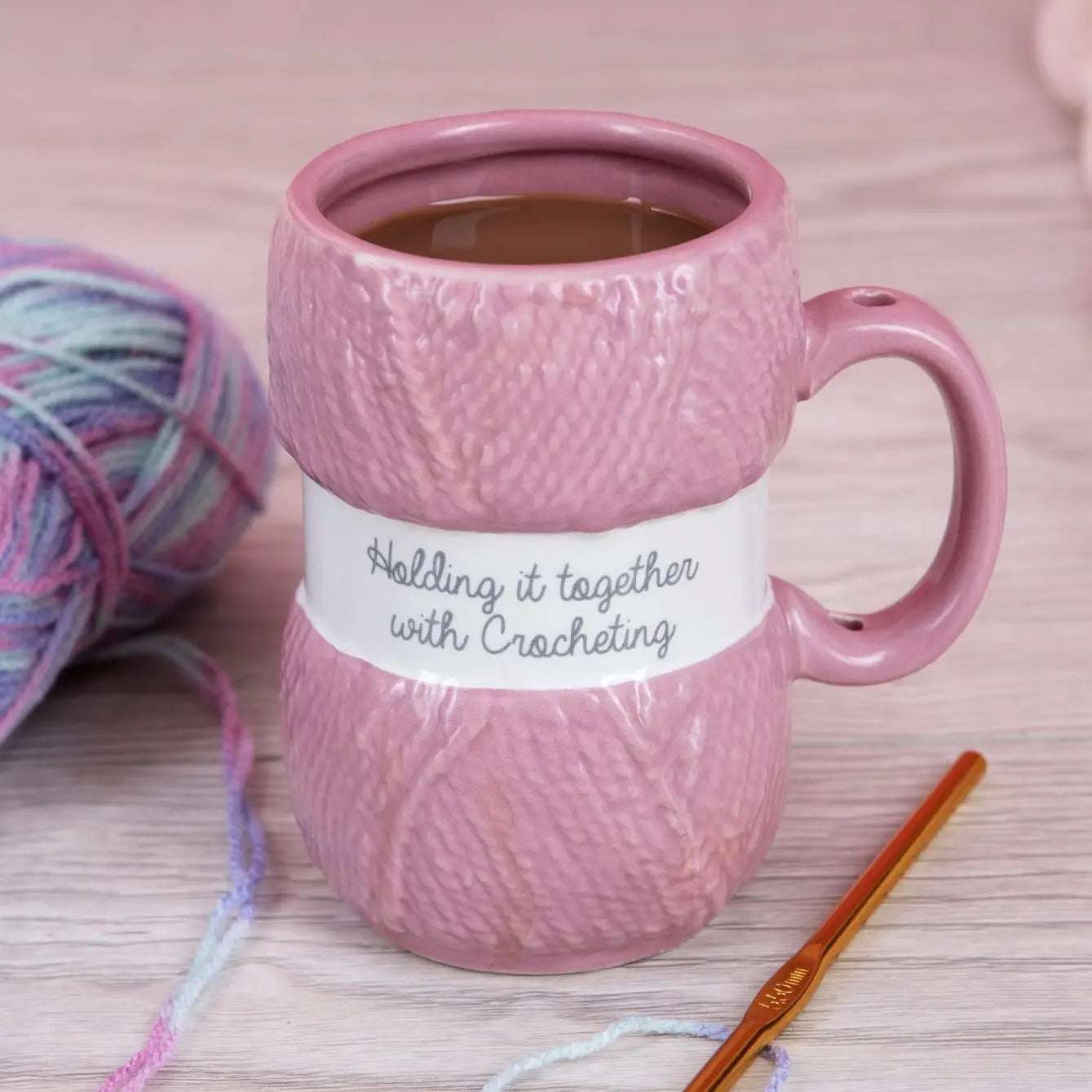 Rosa heklekopp som ser ut som et rosa garn-nøste med hull i håndtaket til heklenålen.