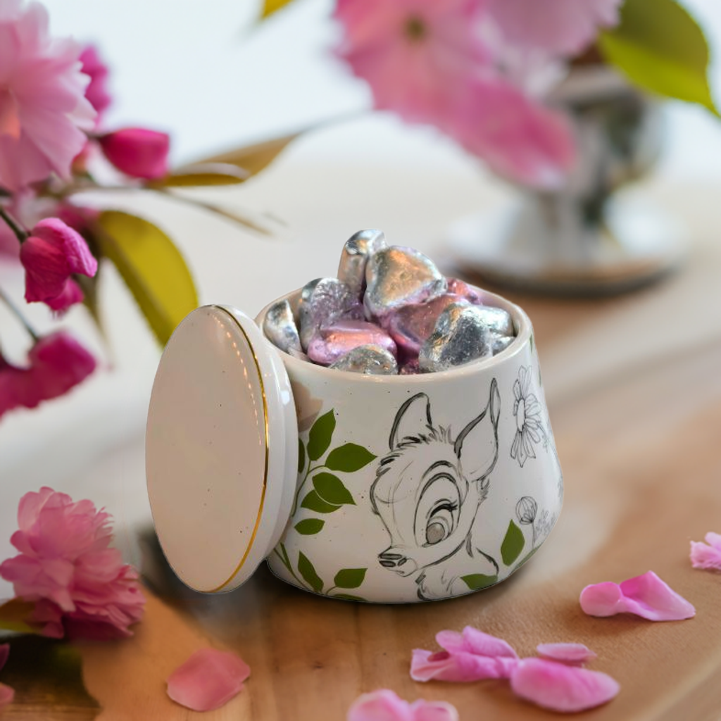 Krukke fra Disney med bambi detaljer som står på et bord med blomster og blader.