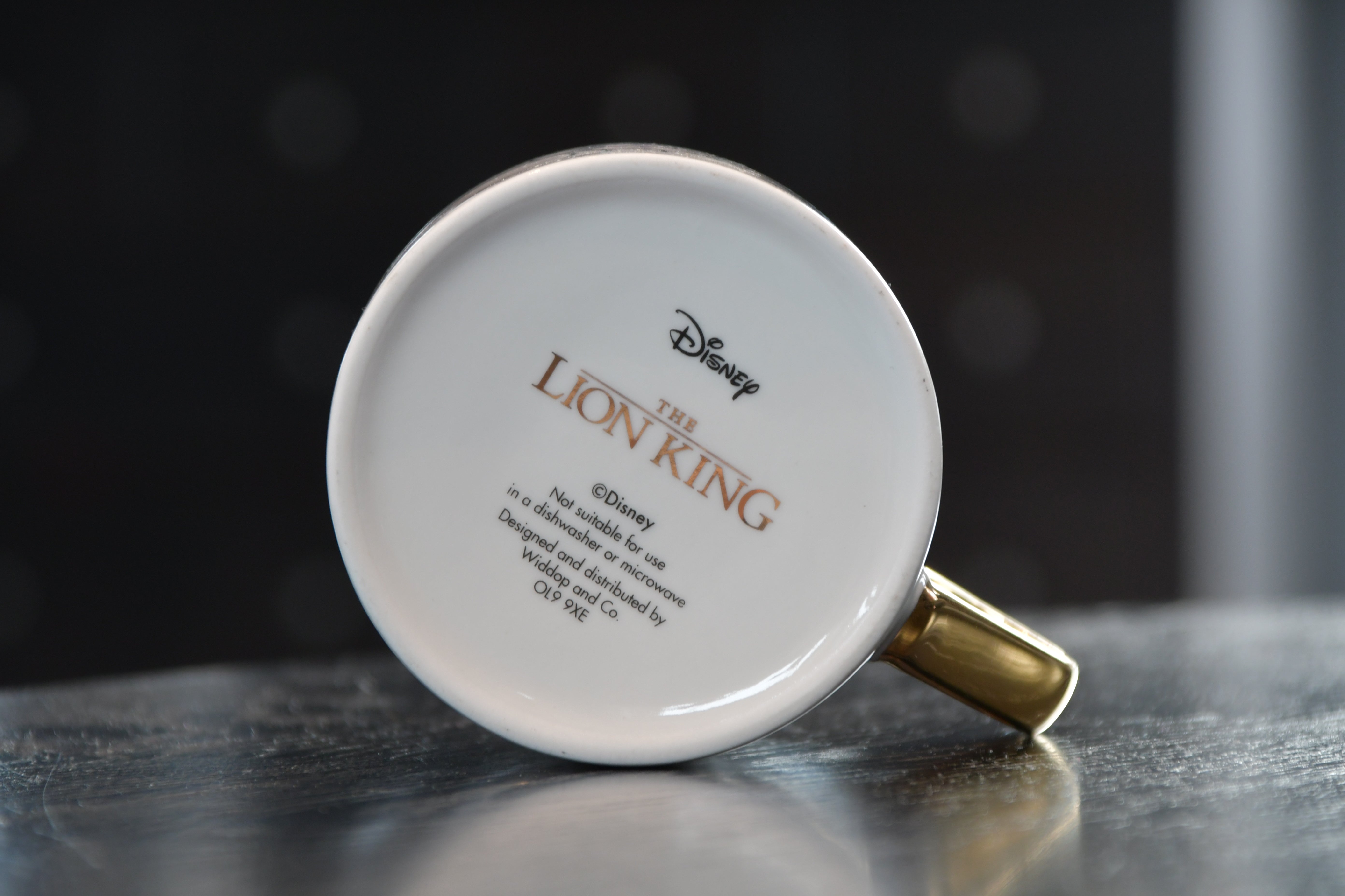 Undersiden av Lion King koppen. Svart og gullskrift