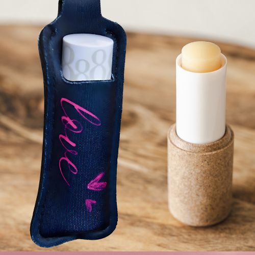 Nøkkelring i sort farge med rosa Love tekst og to rosa hjerter. En leppestift er satt oppi lommen på nøkkelringen.