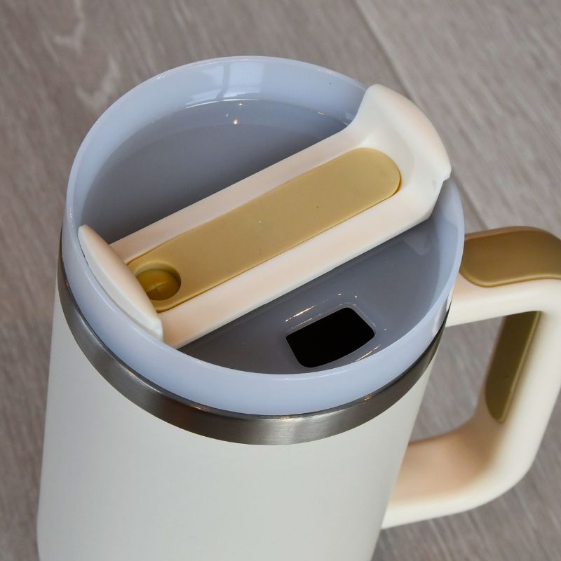 Lokk beige termokopp hvor man kan velge om man vil bruke sugerør eller drikke rett fra koppen. Bare å flippen flippen til siden etter ønske.