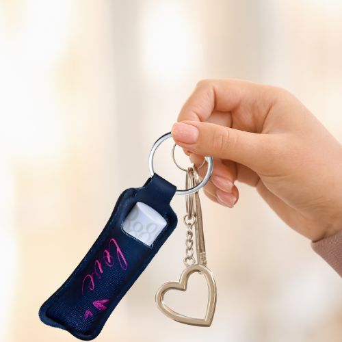 Veske nøkkelknipe i sort med rosa skrift hvor det står LOVE. Den henger på nøkkelknipe sammen med nøkler og et hjerte.