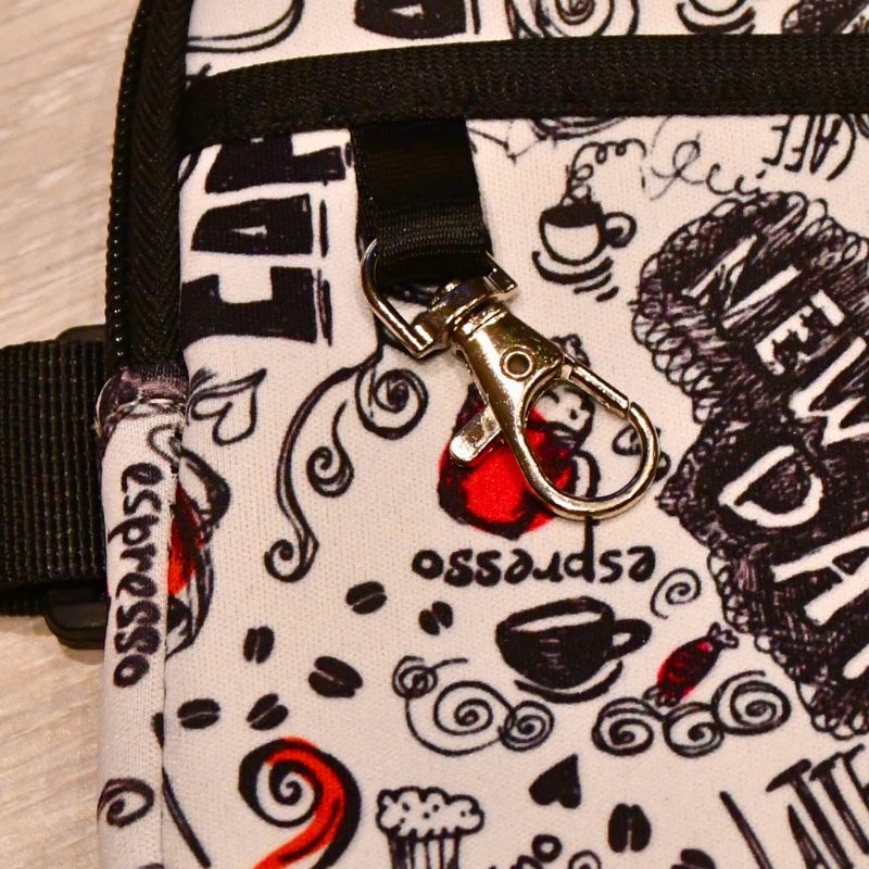 Det følger med en krok på vesken med kaffemotiv så man kan feste det man ønsker på den.