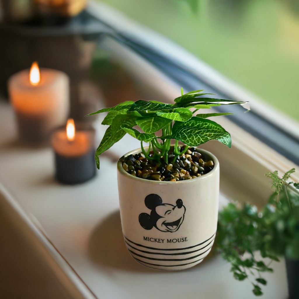 Mikke mus blomsterpotte som står i vindugskarmen sammen med tente lys