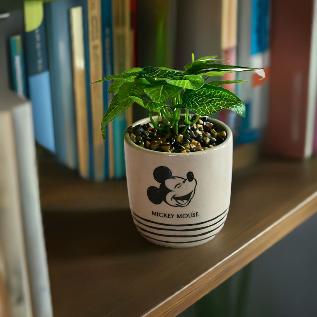 Mikke-mus-blomsterpotte med blomst i. Her står den i en bokhylle.