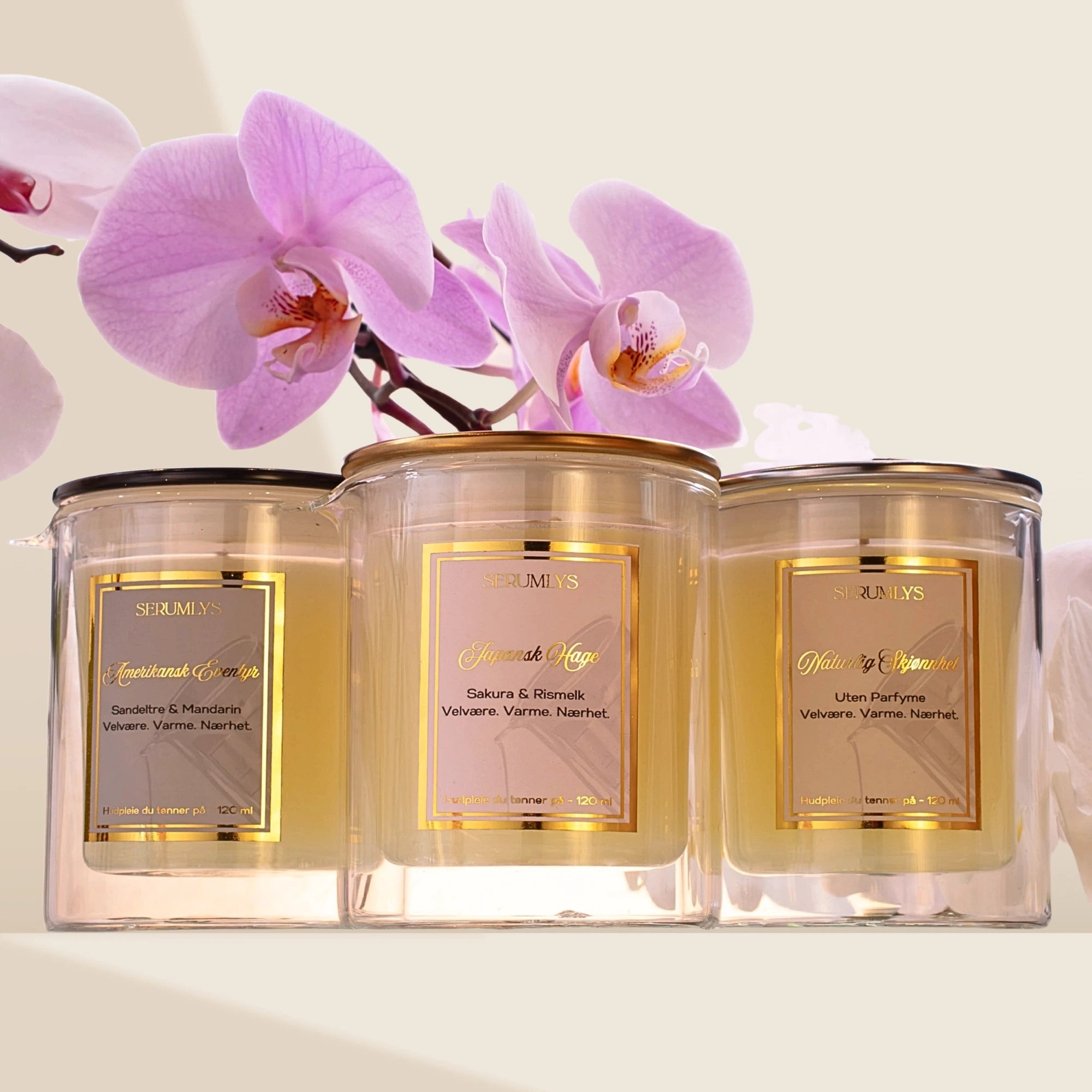 Tre varianter av serumlys. Naturlig hudpleie med næringsrike oljer. Til venstre er den maskuline varianten Amerikansk Eventyr, som har duft av sandeltre og mandarin. I midten er den feminine varianten Japansk Hage, med duft av Sakura og rismelk. Til høyre er en parfymefri variant Naturlig Skjønnhet. Alle har lokk med hver sin farge. Etikettene med gullkant og gullskrift. Et luksuriøst og eksklusivt hudpleieprodukt, laget for å gi brukeren et øyeblikk av ro og pleie til egen kropp.