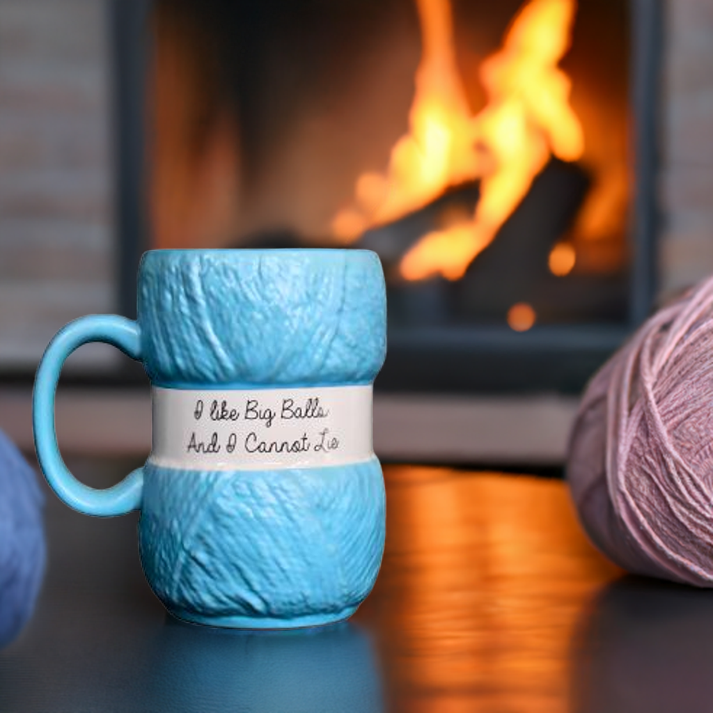 Blaa strikke kopp med peis i bagrunnen og garn-nøste på bordet