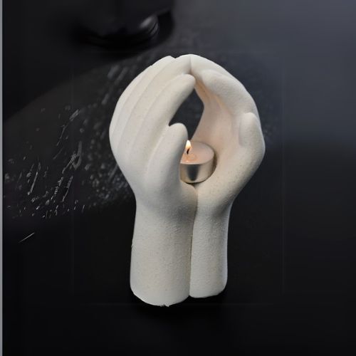 Telys holder to hender Hvit/beige farge. Telyset er tent.