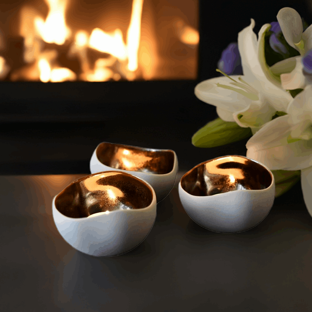 Kremhvit og brånse telysholdere forran peisen. 3stk nydelige håndlagde telys holdere i bruk. Skaper en stemning i hjemmet når telysene blir tent og lyser på bronsefargen inni holderene. Unik interiør som virkelig gir hjemmet det lille ekstra. Dekorasjon til hjemme som varer år etter år. Håndlaget i Frankrike.