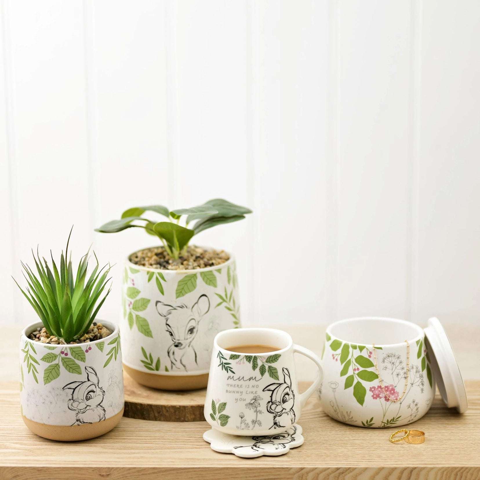 Trampe kaffekopp med brikke ved siden av en krukke og to blomsterpotter i samme Disney Home serie.