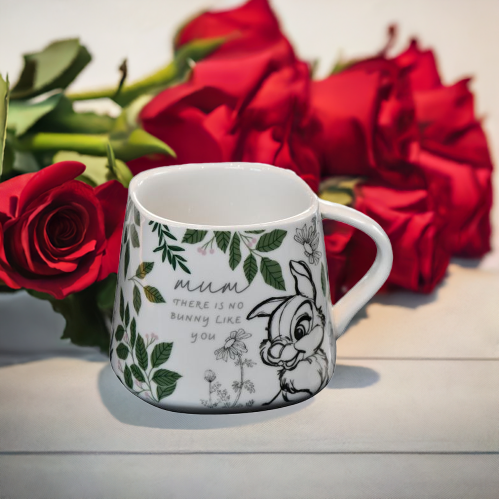 Trampe kopp med tekst fra Disney forran en bukett med røde roser