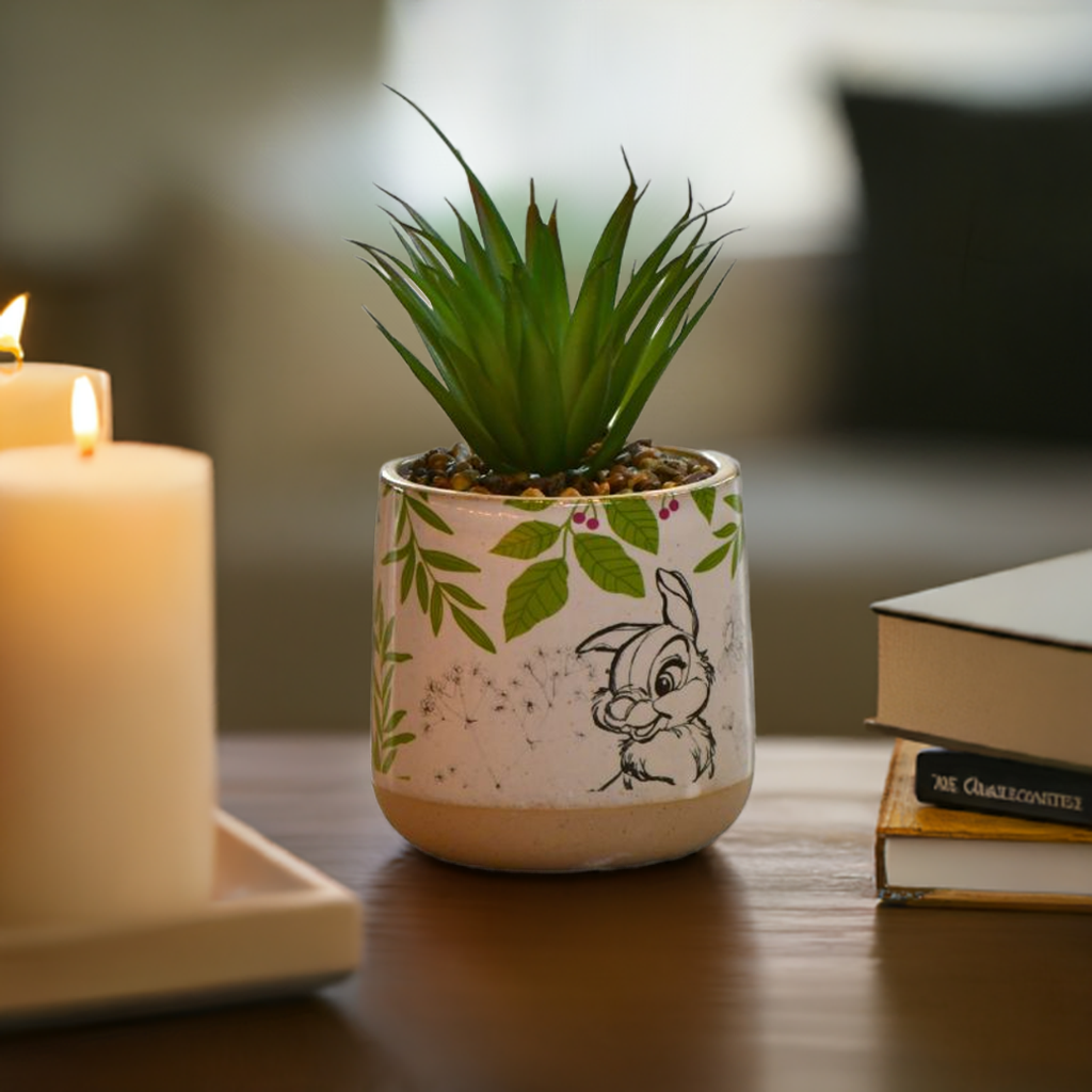 Trampe potteplante fra Disney i bruk på sjenken sammen med lys og bøker