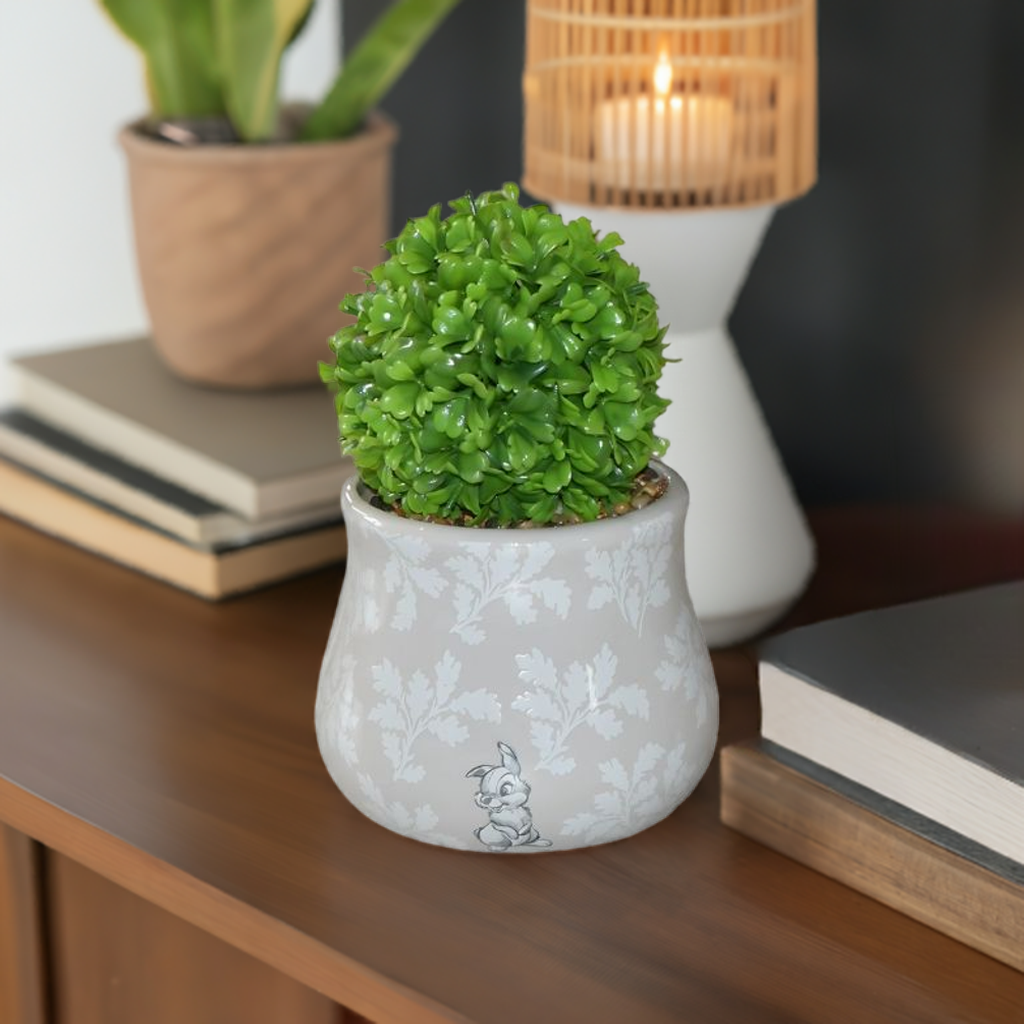 Bambi og tampe potteplante med plante i. Her står den på en komode med pynt på.