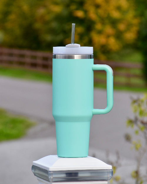 Turkis tumbler med sugerør og håndtak. Kan graveres med navn eller tekst om ønskelig. Sølvring, silikongrep på håndtaket for godt grep. Lokk med mulighet for sugerør eller å drikke rett fra lokket. Kan lukkes og åpnes i toppen. Delene kan taes fra hverandre ved vasking. Lasergravering av personlig tekst som er perfekt å gi i gave.