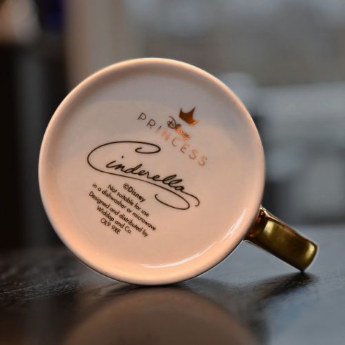 Undersiden av Askepott kruset. Gullskrift som gjør den veldig flott, blandet med svart skrift.