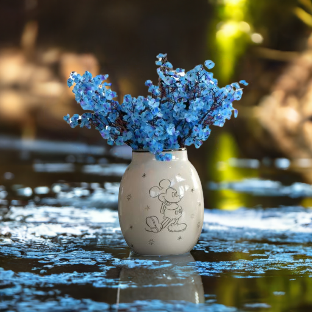 Mikke mus vase fra Disney med blå blomster oppi. Rundt vasen er det masse blå blader fra blomstene.