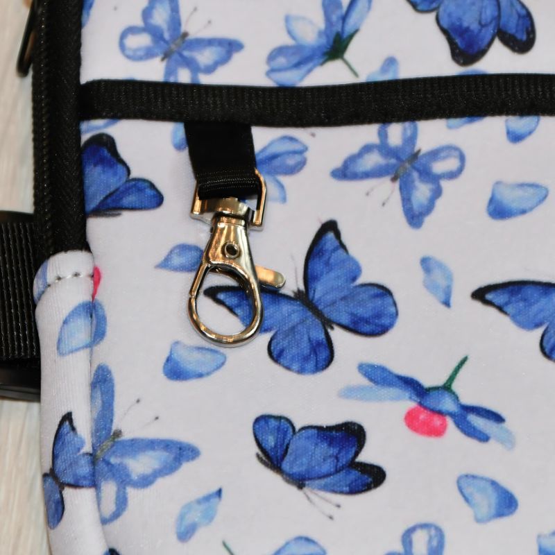 Veske til tumbler med blå sommerfugl motiv kommer også med krok på seg så du enkelt kan feste diverse ting på.