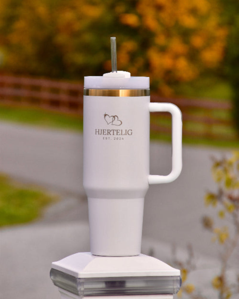 Hvit tumbler med gullkant og Hjertelig logo