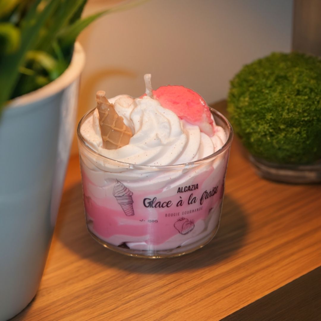 Et håndlaget duftlys med jordbær og vanilje duft. Stående på et bord ved siden av to planter