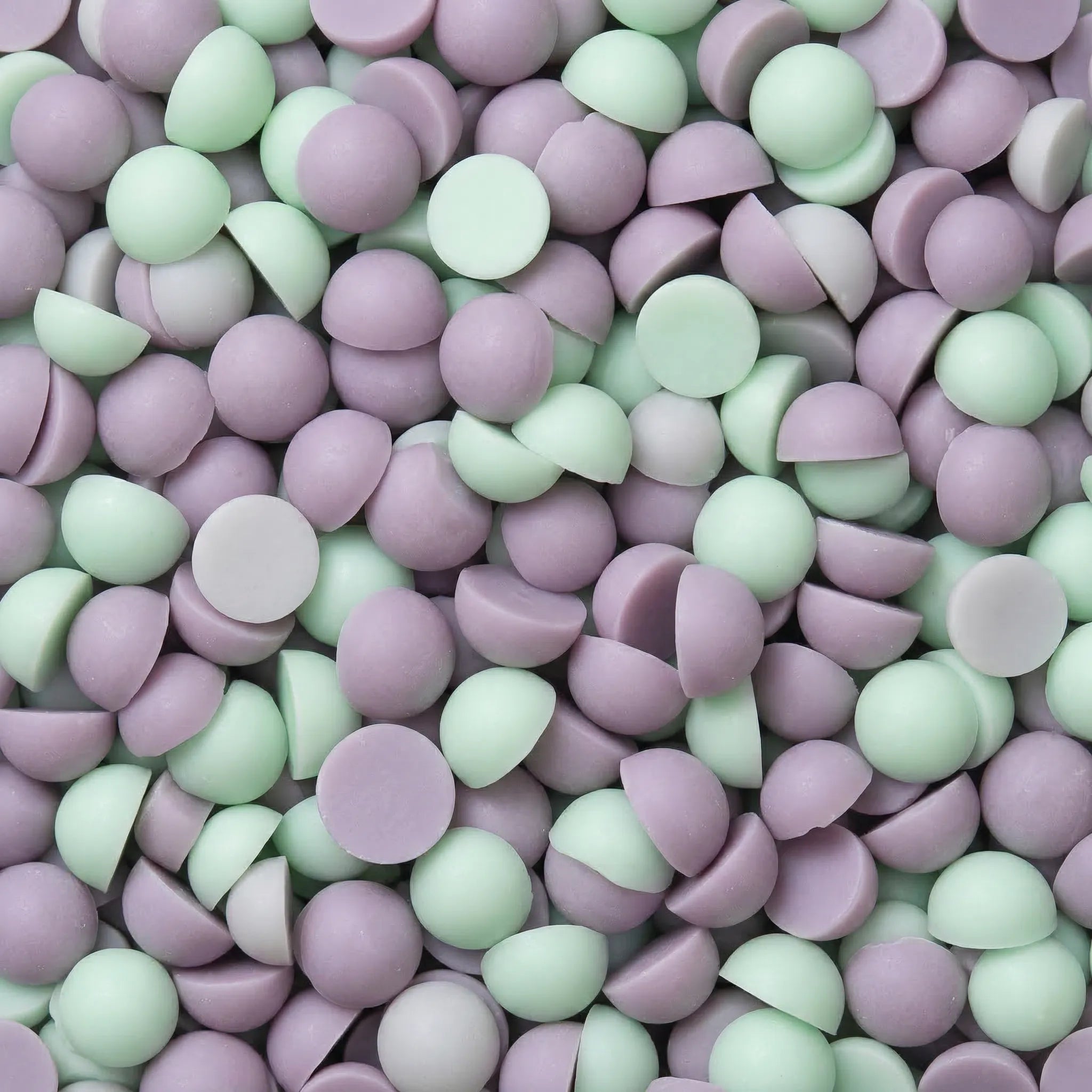 Et nærbilde av duftvokskuler. Små grønne og beige kuler med duft av pistasj og marchmallows. Håndlaget duftvoks fra Norge med bivoks og soyavoks.