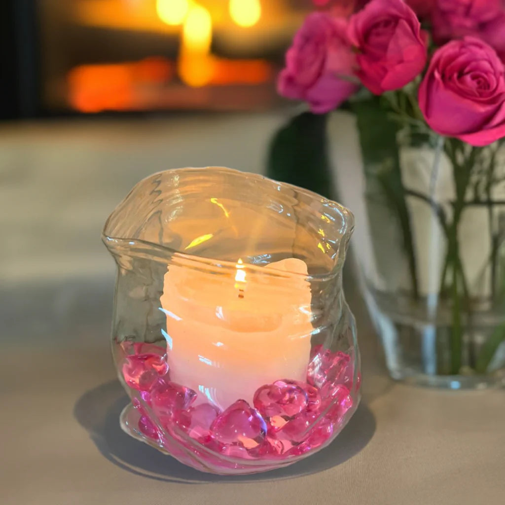 En glassbolle som er formet som et åpnet ziplock pose. På bildet er denne brukt til kubbelys og rosa hjerter som pynt i bunn av bollen. I bakgrunnen ser man rosa roser