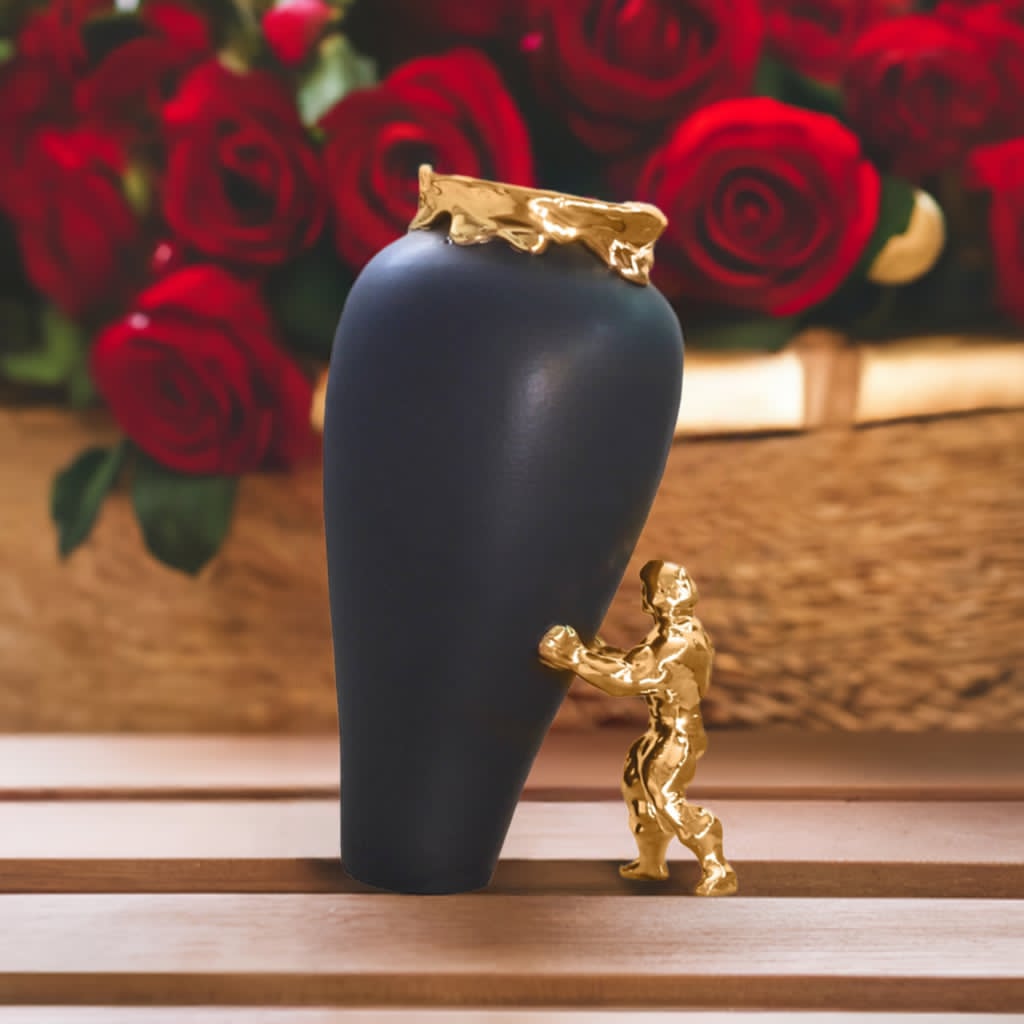 En keramikkvase i sort farge med 24 karat gullbelagt superhelt og kant. Superhelten støtter opp vasen, som ser ut til å skal falle.