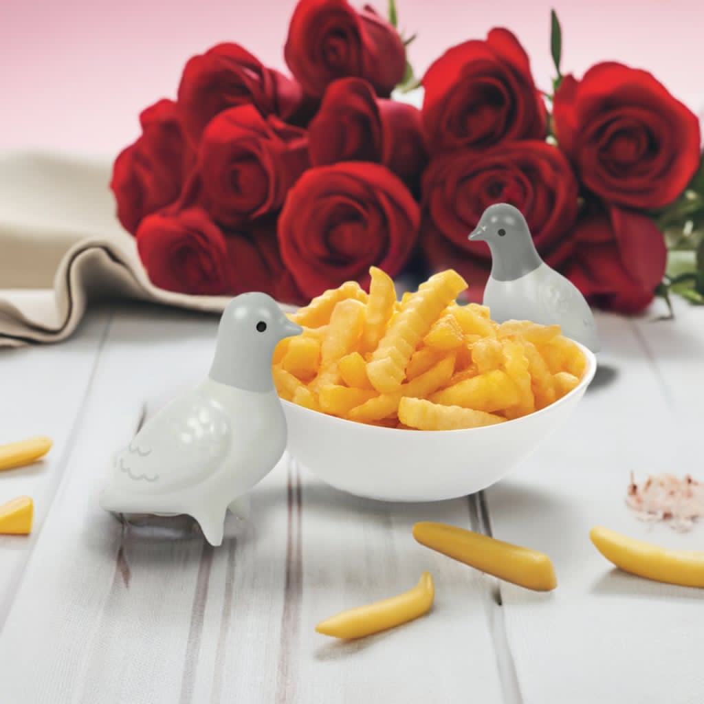 Salt og pepper bøsse i bruk. Det ser ut som at duene har en romantisk middag med pommes frittes forran en bukett med roser.