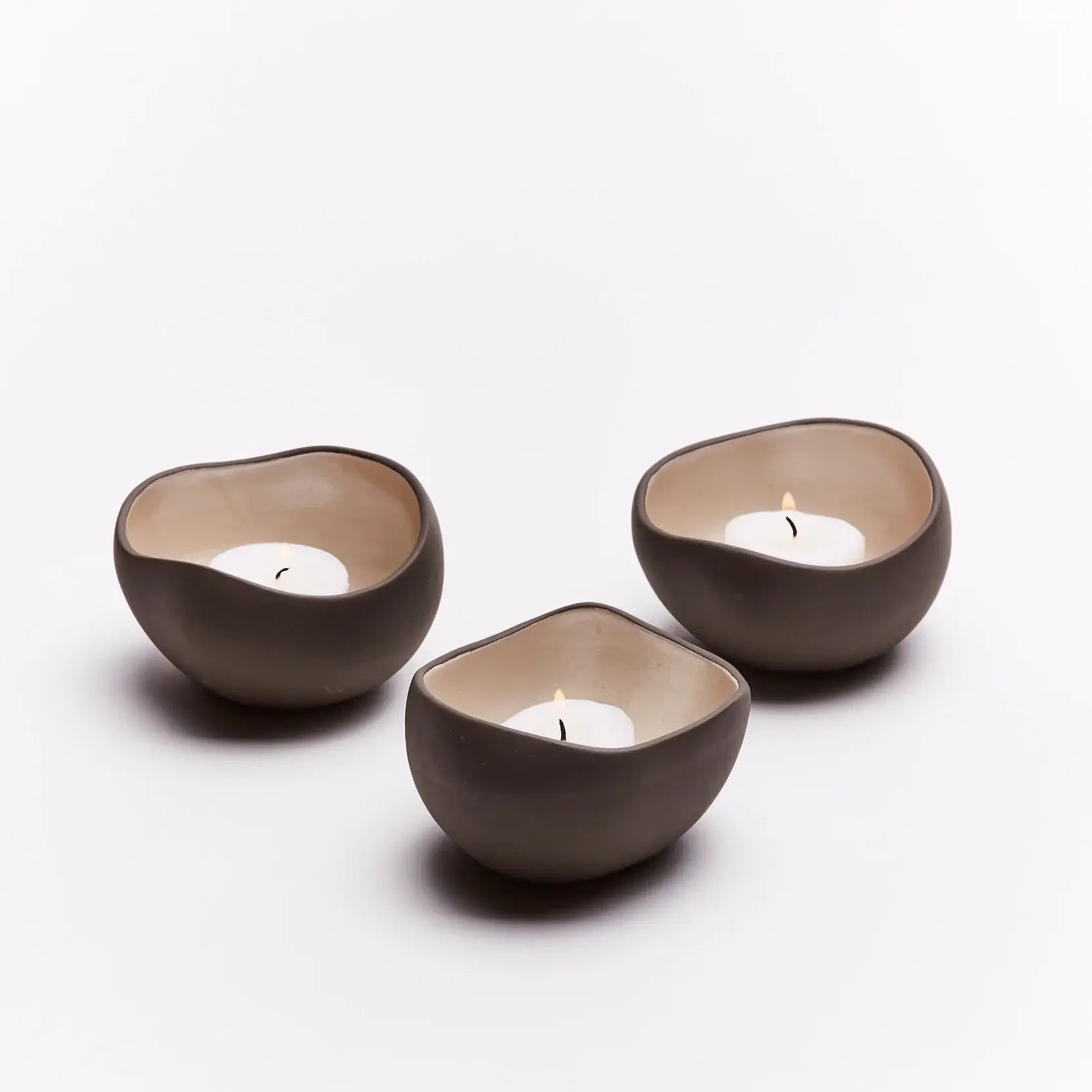 Tre telysholdere med telys som brenner. Når telysene er tent gir dette en ro til kropp og sjel. Håndlaget av keramikk i frankrike. Hver telysholder er derfor unik og spesiell.