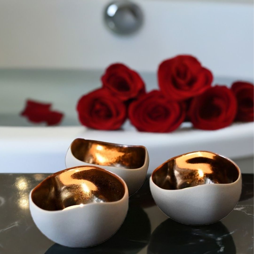 Telys bronse og kremhvit forran badekaret. Lager stemning i et hvert rom.