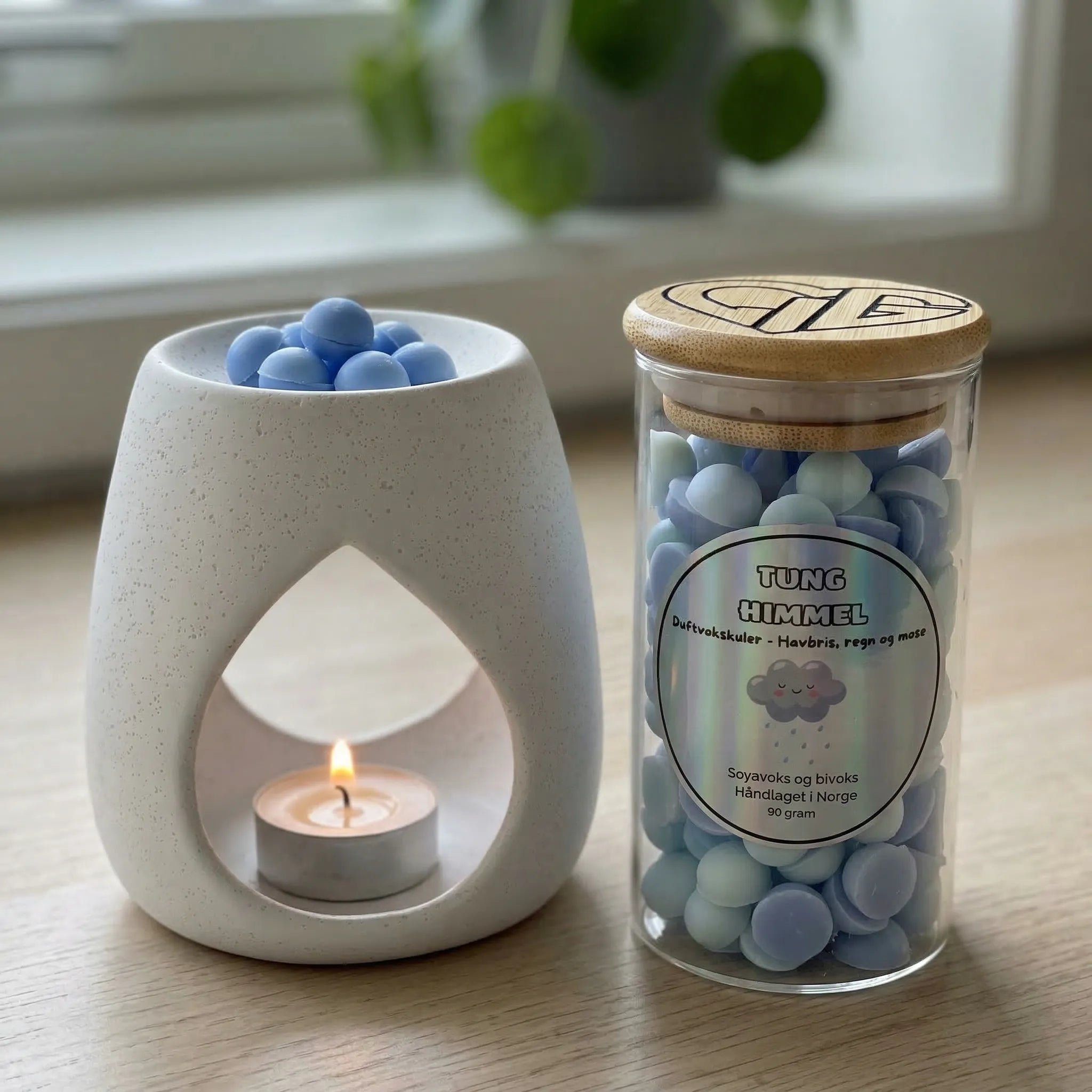 Duftvoks i glass med duft av havbris, regn og mose. Duften heter Tung Himmel og inneholder 90g voks, laget av soyavoks og bivoks. En duftbrenner med telys smelter noen vokskuler, og sprer den lette friske duften ut i rommet. Håndlaget i norge med kjærlighet