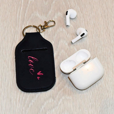 Airpodsveske svart med rosa skrift hvor det står Love. 