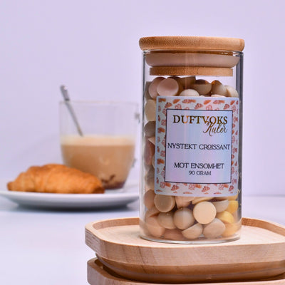 Duftvoks kuler som gir følelsen av å sitte på et bakeri i Frankrike. Kjenn den herlige duften av nystekt croissant i ditt egent hjem. I bakgrunnen er en tallerken med croissant og en kaffekopp. Duftkulene er laget av soyavoks, og disse kommer i en flott glasskrukke med bambuslokk. Føler du deg ensom, eller kanskje du har en venn som sliter med ensomhet akkurat nå? Disse duftvokskulene har vi dedikert til disse stundene. Du er ikke aleine. Smelt noen vokskuler og kjenn den herlige duften fylle rommet. 