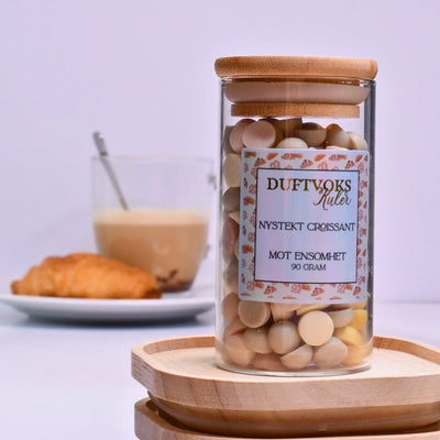 Duftvoks kuler som gir følelsen av å sitte på et bakeri i Frankrike. Kjenn den herlige duften av nystekt croissant i ditt egent hjem. I bakgrunnen er en tallerken med croissant og en kaffekopp. Duftkulene er laget av soyavoks, og disse kommer i en flott glasskrukke med bambuslokk. Føler du deg ensom, eller kanskje du har en venn som sliter med ensomhet akkurat nå? Disse duftvokskulene har vi dedikert til disse stundene. Du er ikke aleine. Smelt noen vokskuler og kjenn den herlige duften fylle rommet. 