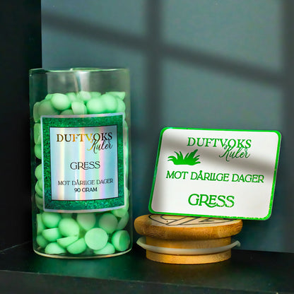 Små søte duftvoks kuler i en glasskrukke. Lokket er av, og følelses-kortet står vesiden av oppå lokket. Man kan se skygger fra vinduget. 