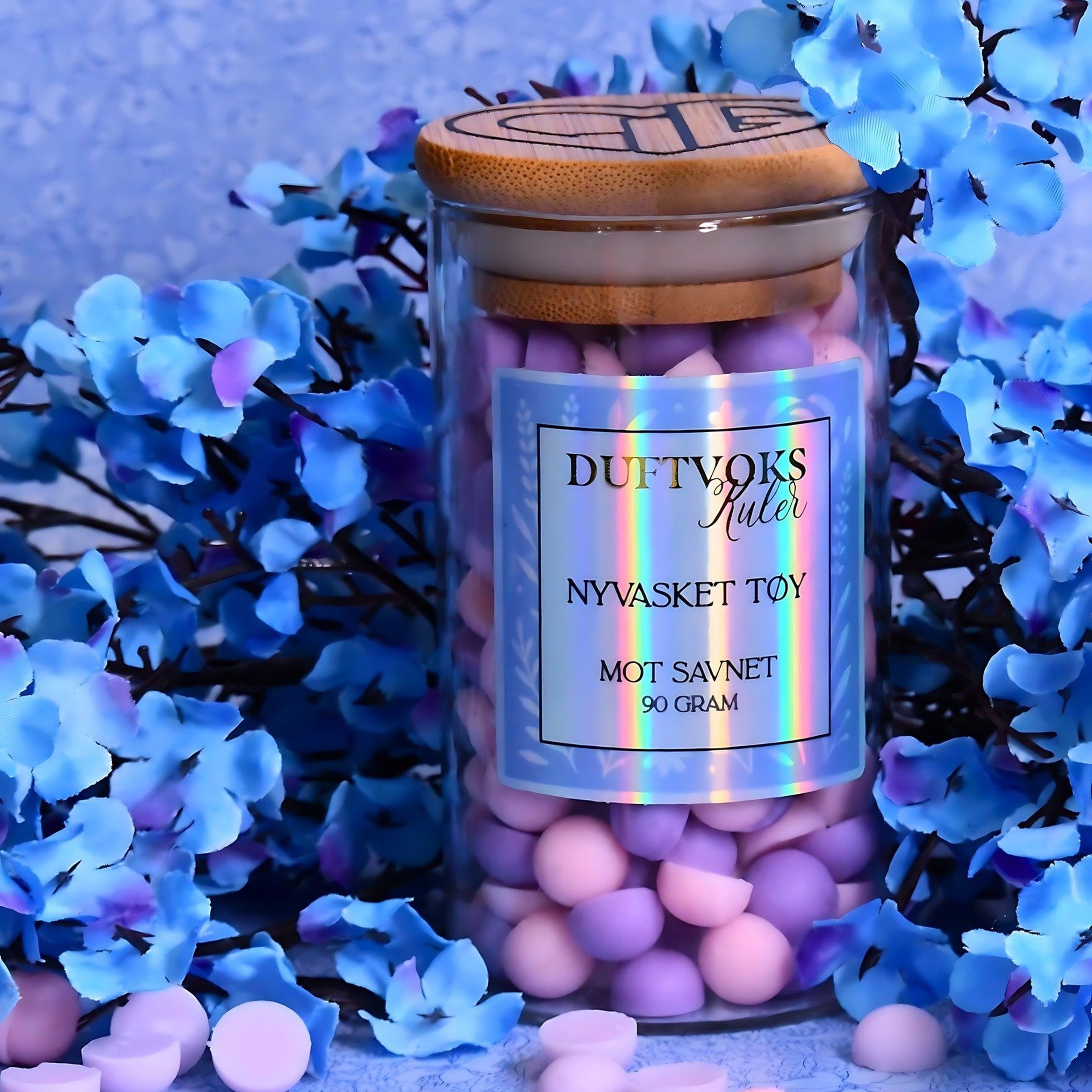 Duftvoks kuler i glasskrukke mot savnet. 90 gram med duft av nyvasket tøy. Blomster i bakgrunnen og kuler som ligger rundt. Tar seg godt ut som pynt i stuen. 