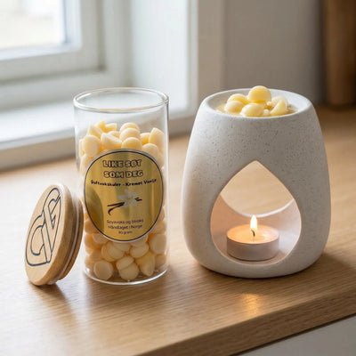 Duftvokskuler i lys gul farge i glass med en duftbrenner ved siden av. Glasset innehodler 90g duftvoks. Noen vokskuler smelter i duftbrenneren og sprer herlig myk duft av kremet vanilje ut i rommet. Voksen er håndlaget i norge med soyavoks og bivoks.