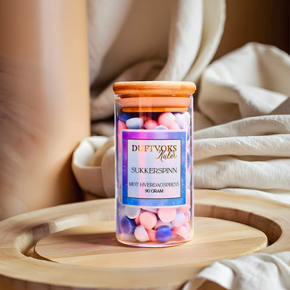 Sukkerspinn duftvokskuler kommer i en nydelig glasskrukke som tar seg godt ut i stuen. Disse søte små kulene fyller romemt med en herlig nostalgisk lukt av sukkerspinn. Drøm deg tilbake til tiden der man ikke visste hva beskymringer og hverdagspress virkelig var. 