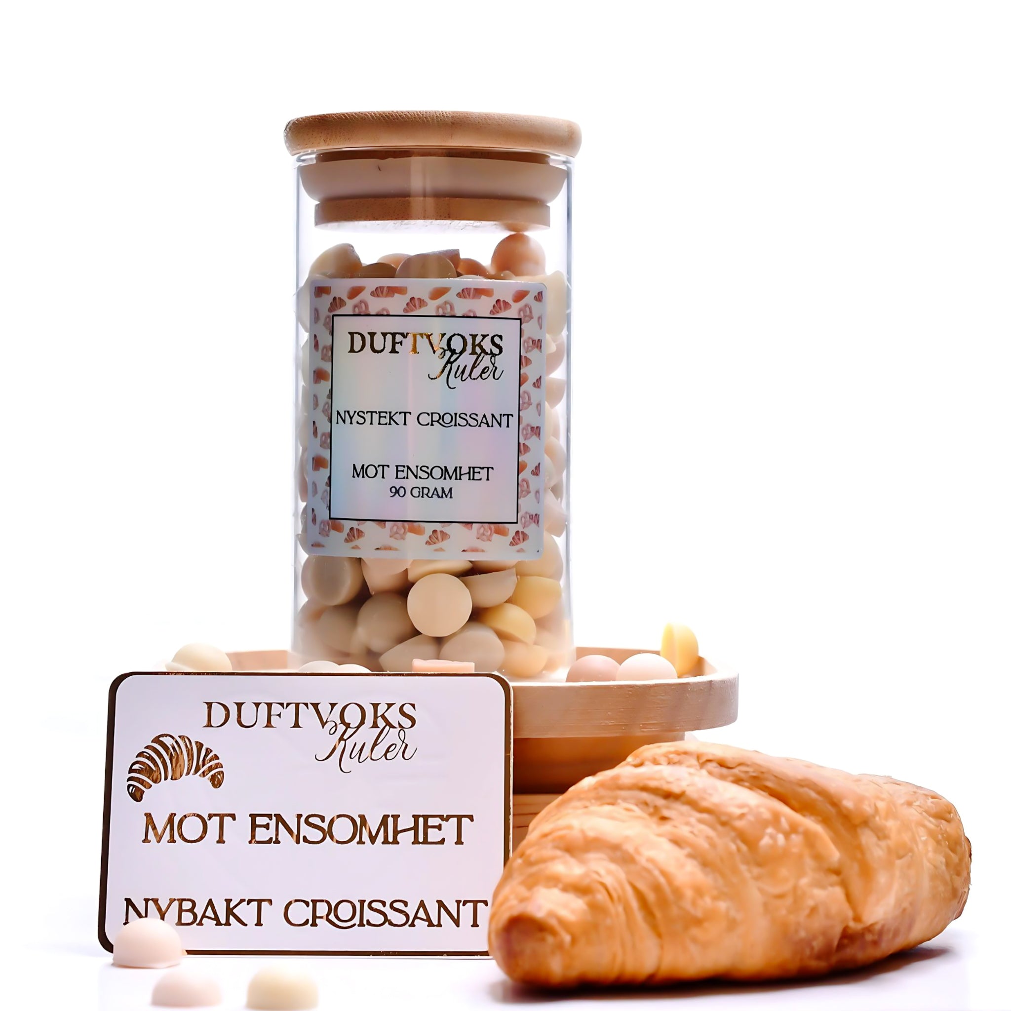 Duftvoks som fyller rommet med nystekte bakevarer. På bilde ser du de søte håndlagde kulene av soyavoks i en nydelig glasskrukke. Croissanten ligger vesidenav og duftvoks kortet som følger med står oppreist. På kortet står det om duftvokskulene som er spesielt laget til deg som føler deg litt ekstra ensom akkurat nå. Smelt noen kuler og drøm deg vekk mens rommet fylles med lukten av bakevarer.