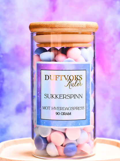 Herlige duftvokskuler laget av soyavoks og duftolje. Kulene er i fargen rosa og blå og har en fantastisk god lukt av sukkerspinn. Nostalgi og gode minner fra barndommen. De kommer i en nydelig glasskrukke med bambuslokk, og du får 90 gram med deilig duft til hjemmet. Smelt noen kuler og bruk tid på deg selv. Fantastisk gave til noen som har en litt for hektisk hverdag og glemmer bort seg selv. 