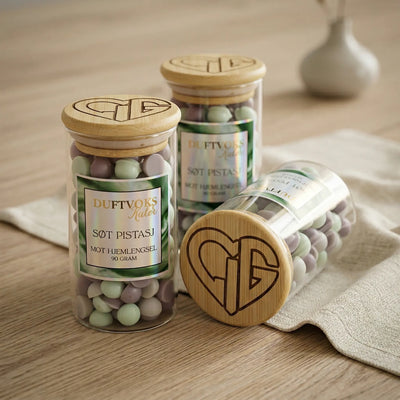 Glass med duftvoks med duft av søt pistasj. En duft som skal lindre følelsen av hjemlengsel. Håndlaget duftvoks med bivoks og soyavoks. Duftvoksen har beige og lys grønn farge. Hvert glass inneholder 90 gram duftvoks. En av flere dufter i serien "sett en duft på dine følelser"